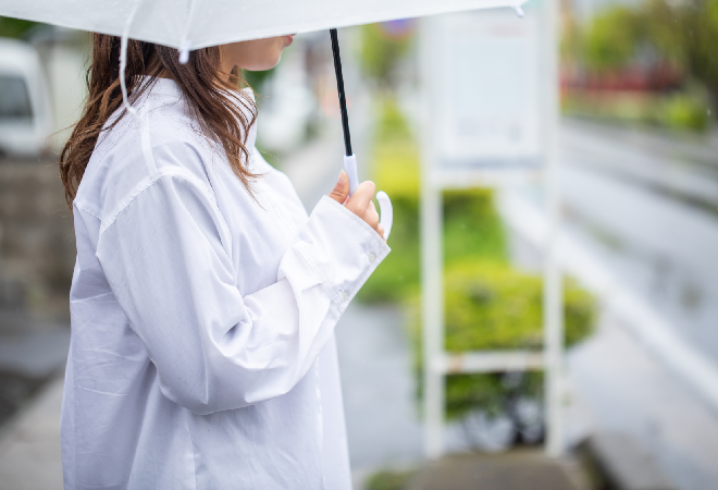 雨の中傘をさし立っている女性の横顔。