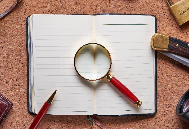 開いたノートの上に虫眼鏡を置いてある画像。