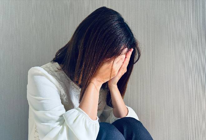 部屋の隅で悩み苦しむ女性の姿。