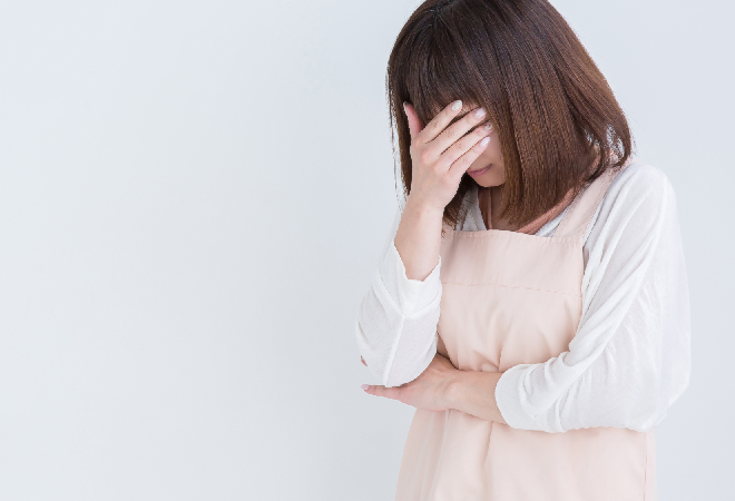 落ち込むエプロン姿の母親。