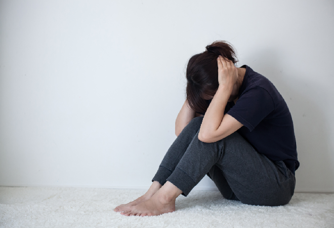 うずくまり耳をふさぐ女性。