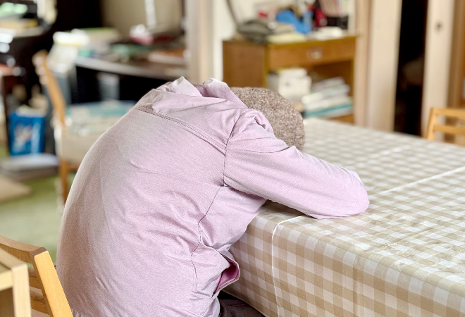 テーブルに突っ伏す高齢女性。