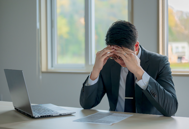 デスクで頭を抱えるビジネスマン。