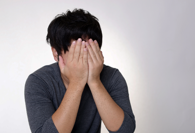 手で顔を覆い落ち込む若者。