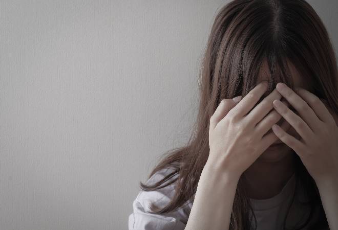 頭を抱え項垂れる女性。