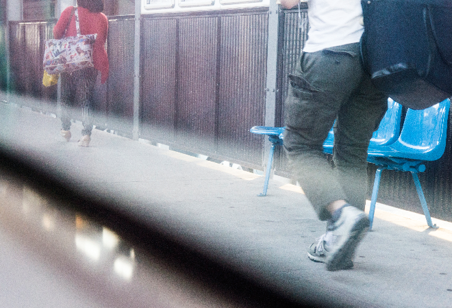 駅のホームを歩く男性の後ろ姿。