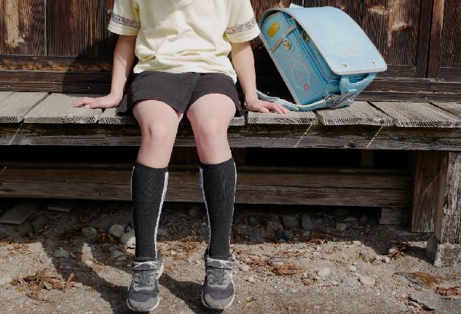 一人寂しく外に座る小学生。