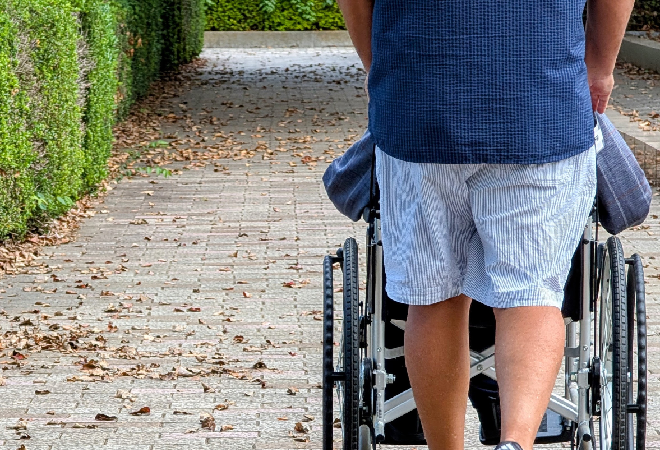 車いすを押す男性の後ろ姿。