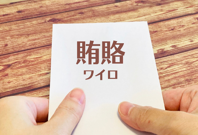 賄賂と書かれた封筒を受け取る手。