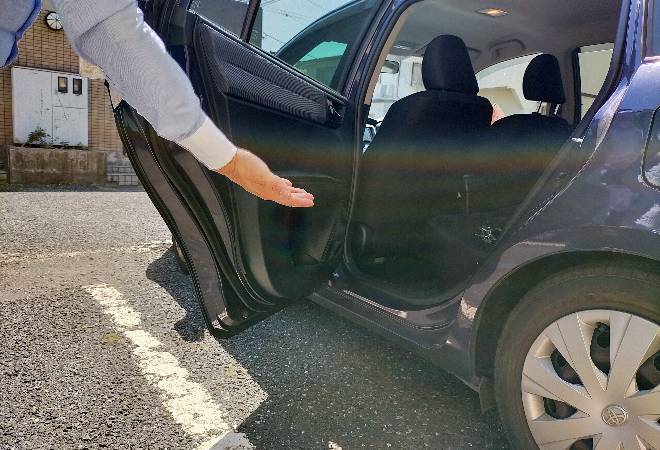車の後部座席を開けている手。