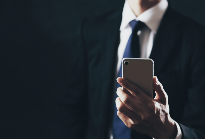 スマホを操作するスーツの男性。