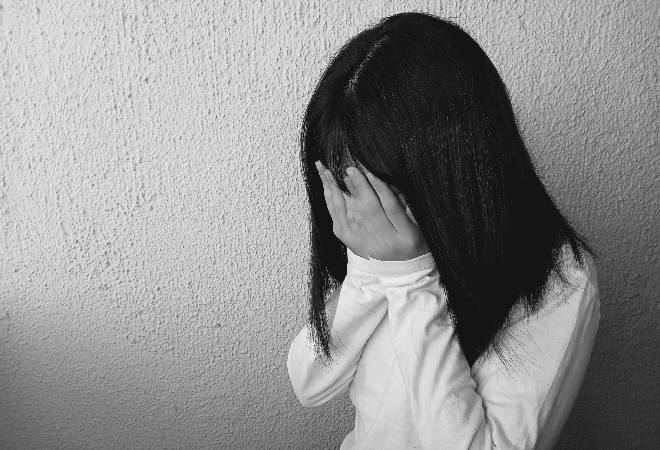 顔を手で覆う女の子のモノクロ写真。