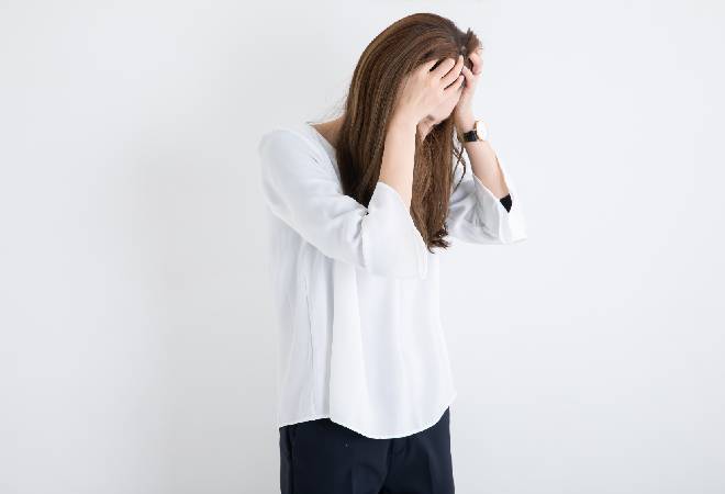 手で顔を覆う女性。