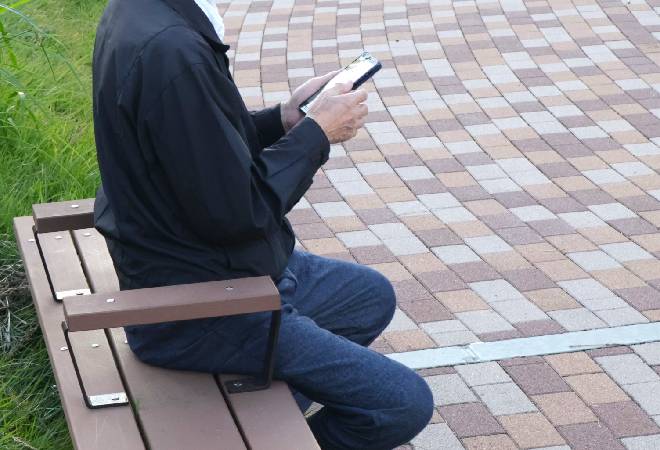 ベンチでスマホを見る男性の横顔。
