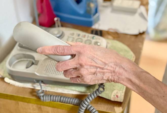 高齢者が受話器を置こうとしている。